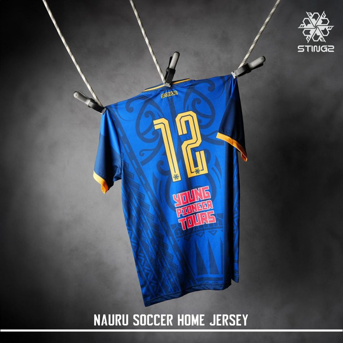 Back of the blue Nauru home jersey with a gold number 12 and tribal pattern, hanging from ropes